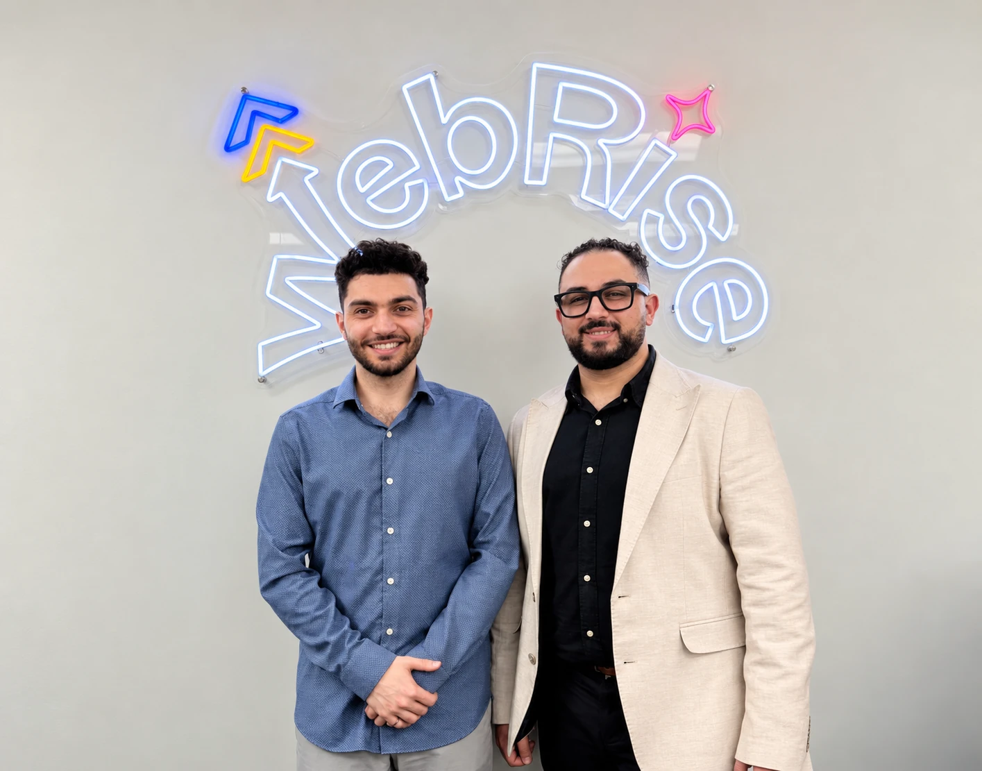 WebRise founders in front of the illuminated sign in their office